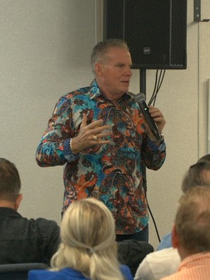 Dr. Eric Gonyon teaching with a microphone at a Kingdom Business Fellowship meeting